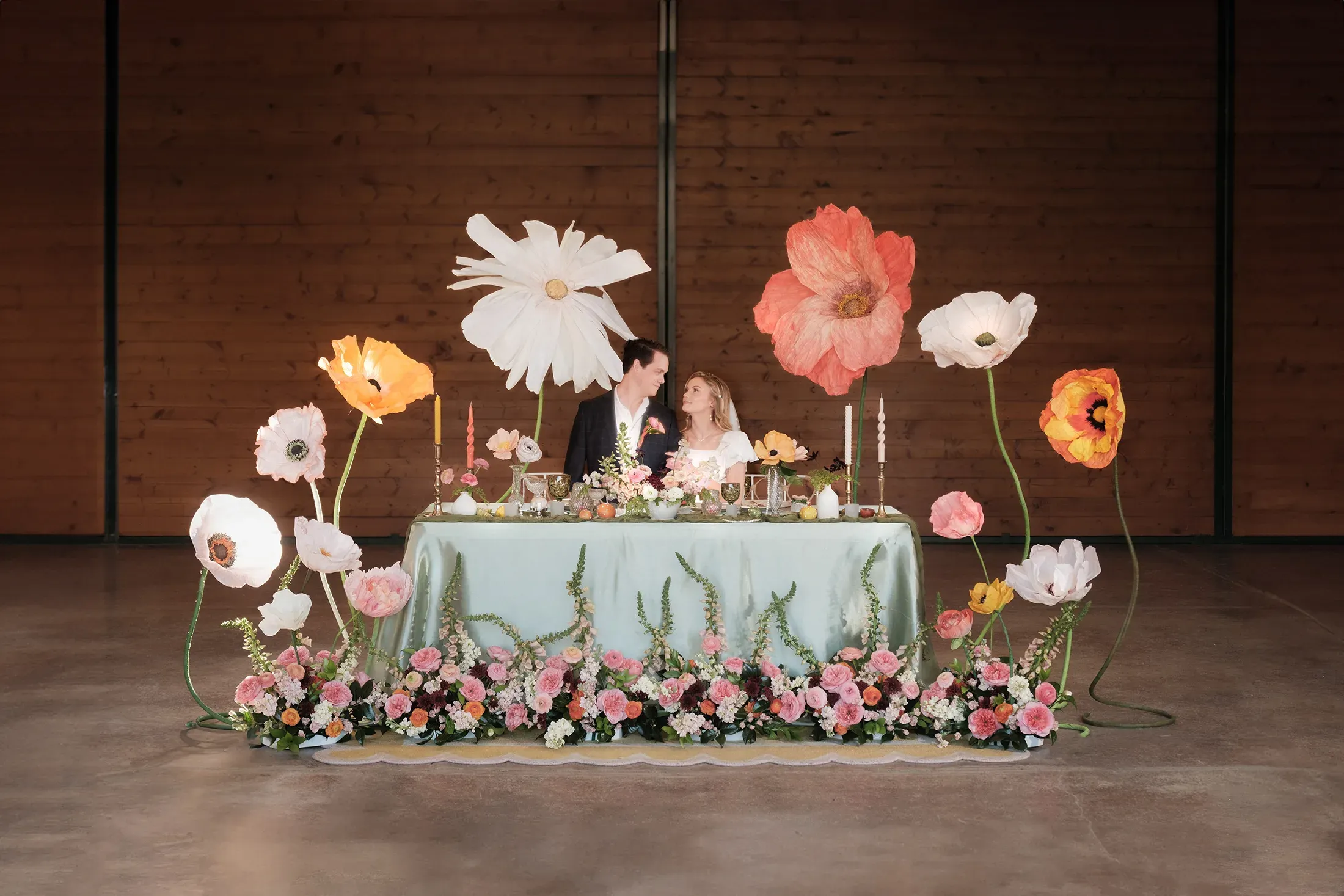 A couple seated at a flower-filled wedding table