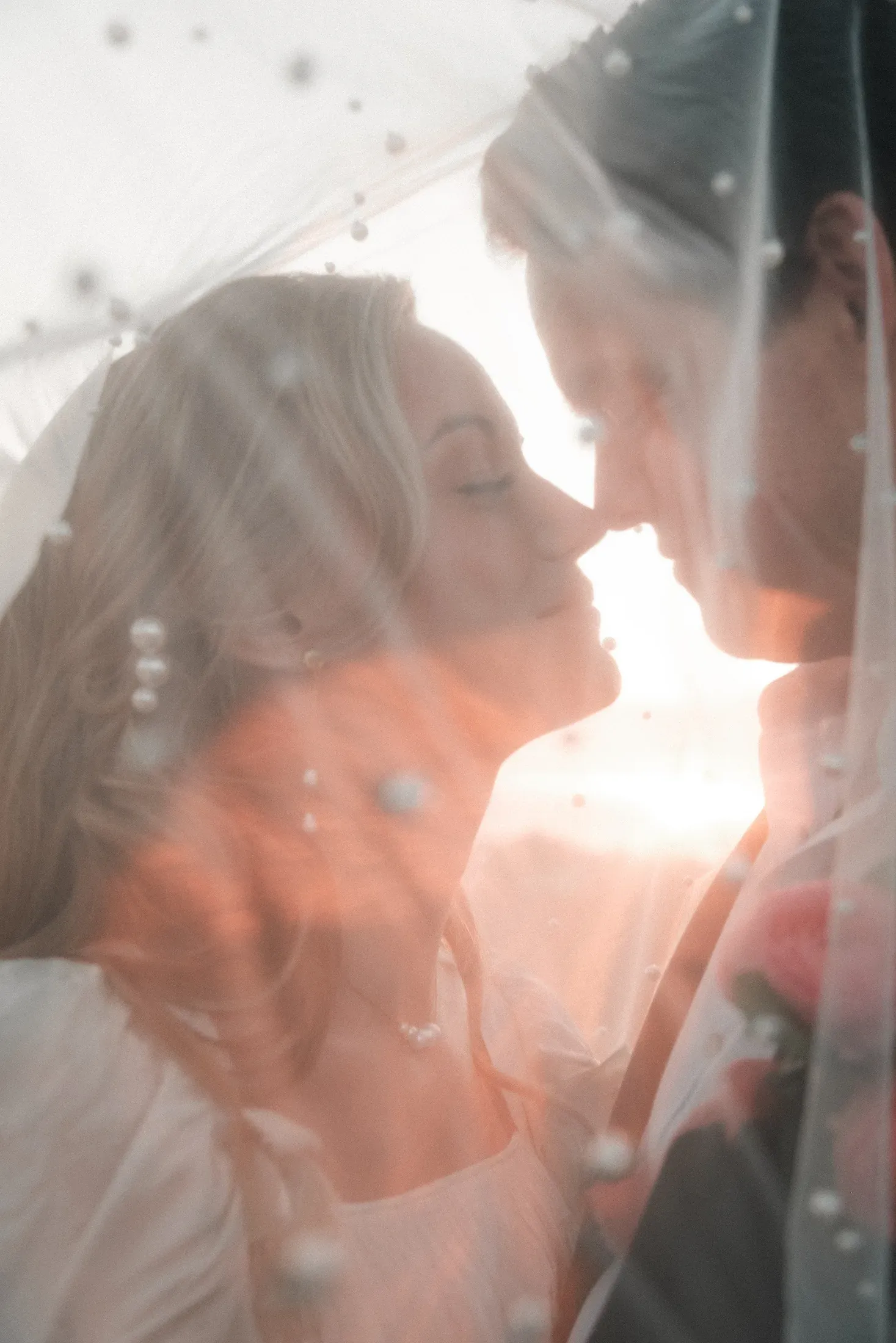 A couple sharing a quiet moment beneath a wedding veil